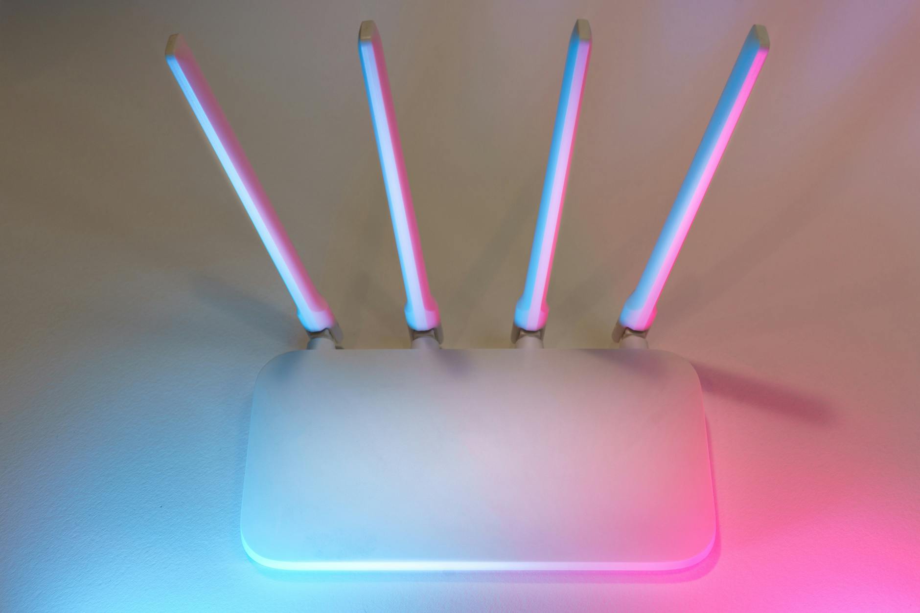 Nowoczesny biały router Wi‑Fi z czterema antenami w niebiesko‑różowym świetle