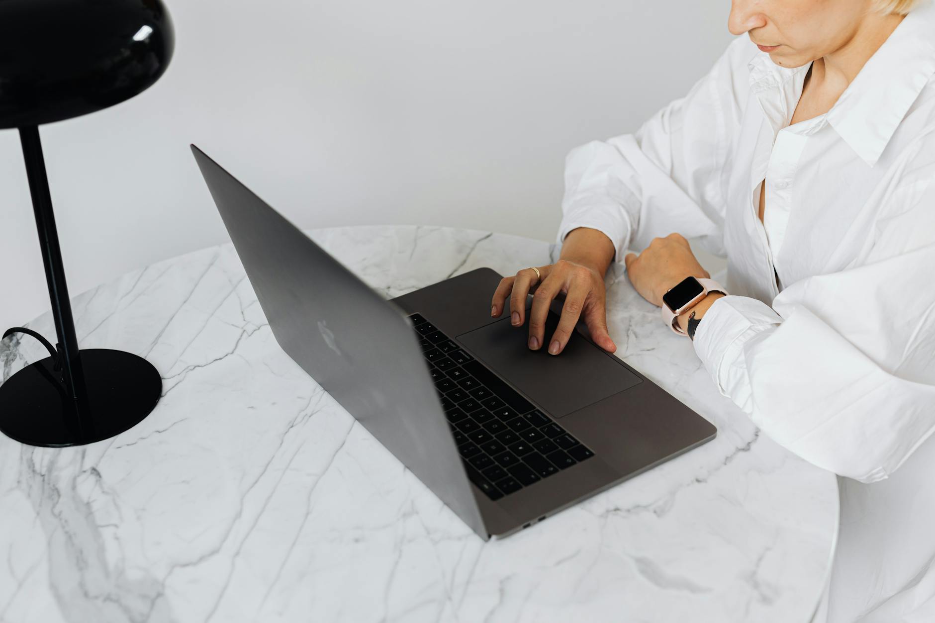 Specjalistka IT przy laptopie przy marmurowym biurku z lampką biurkową